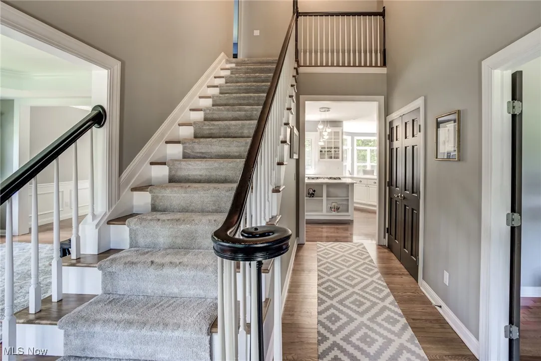 Stairway with wood finished floors and a high ceiling