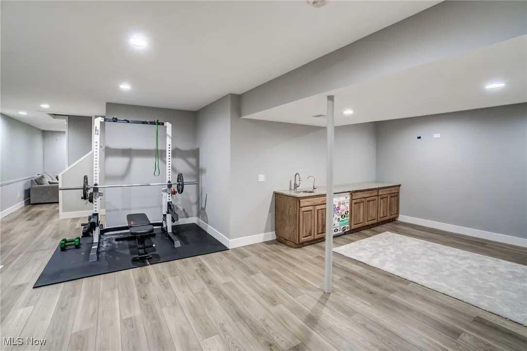 Workout area featuring wet bar, light wood-style floors, and recessed lighting