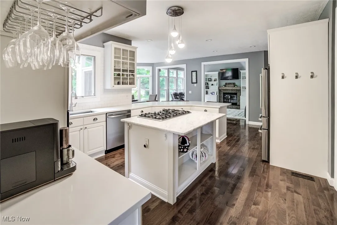 Kitchen featuring stainless steel appliances, a peninsula, light countertops, white cabinets, and glass insert cabinets