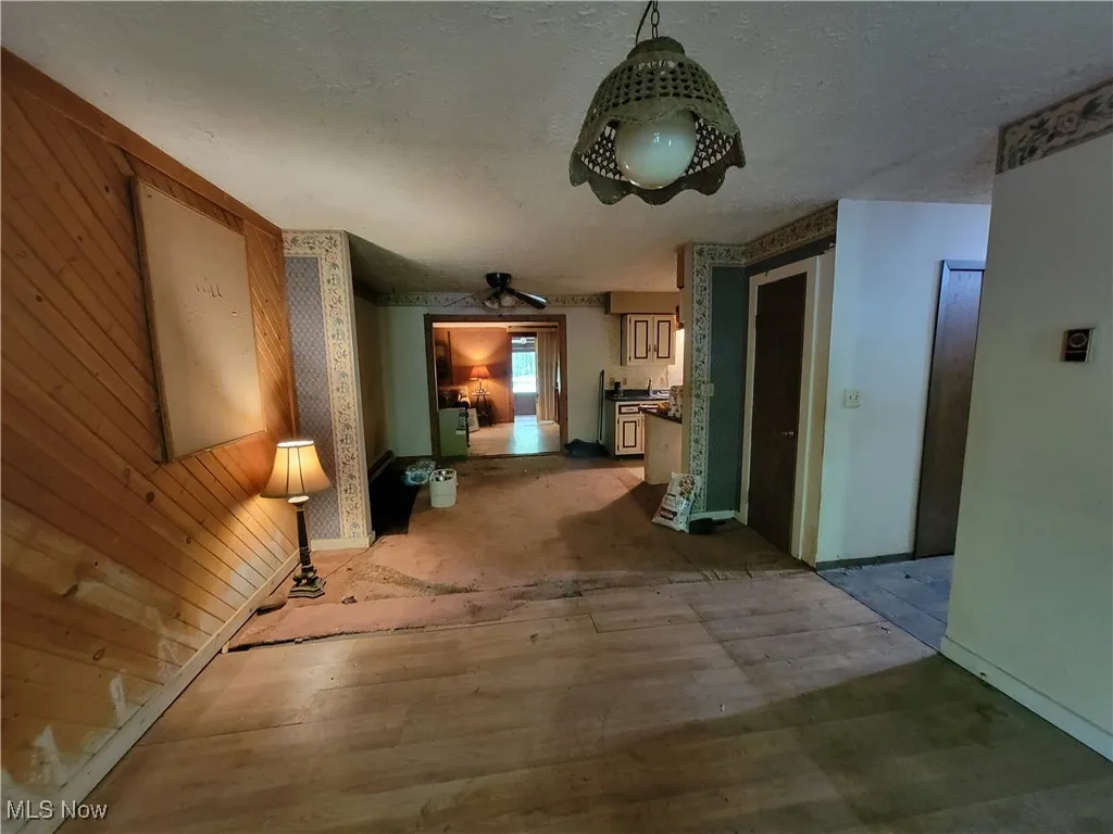 Corridor featuring wooden walls, wood finished floors, and a textured ceiling