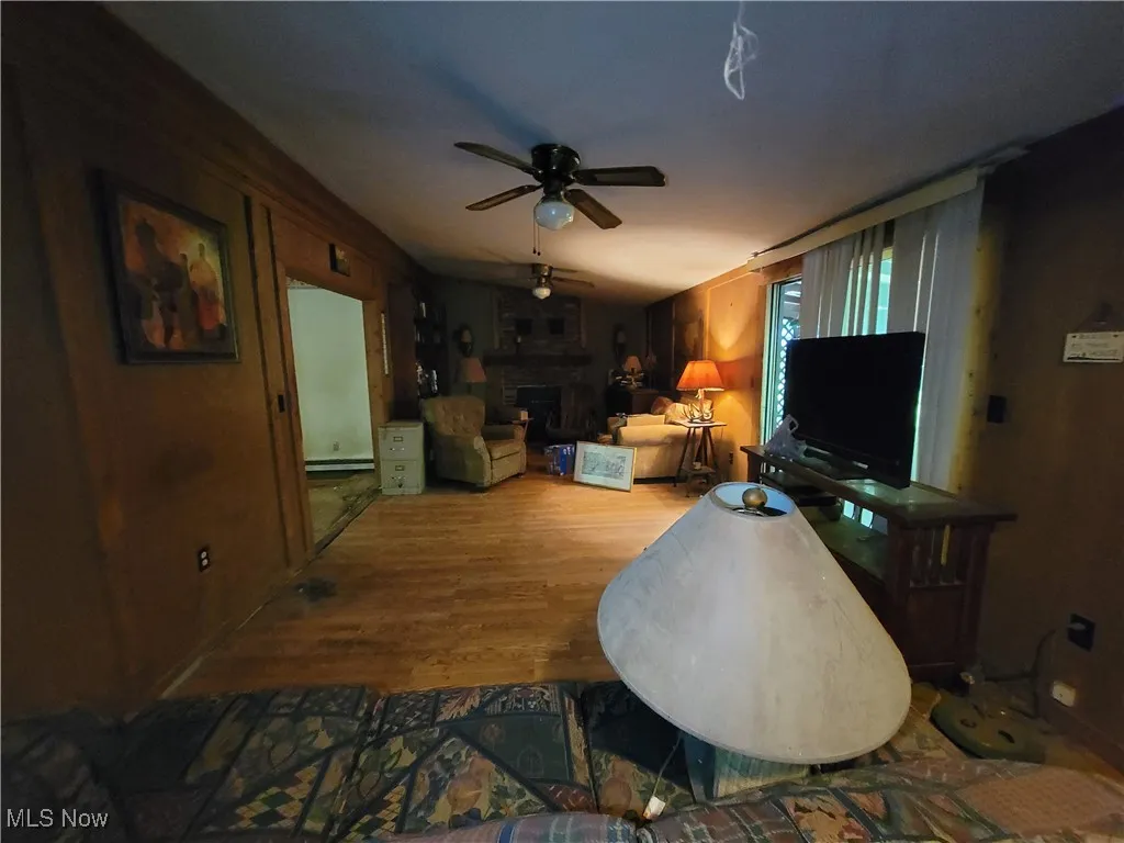 Living room with ceiling fan, wood finished floors, and a fireplace
