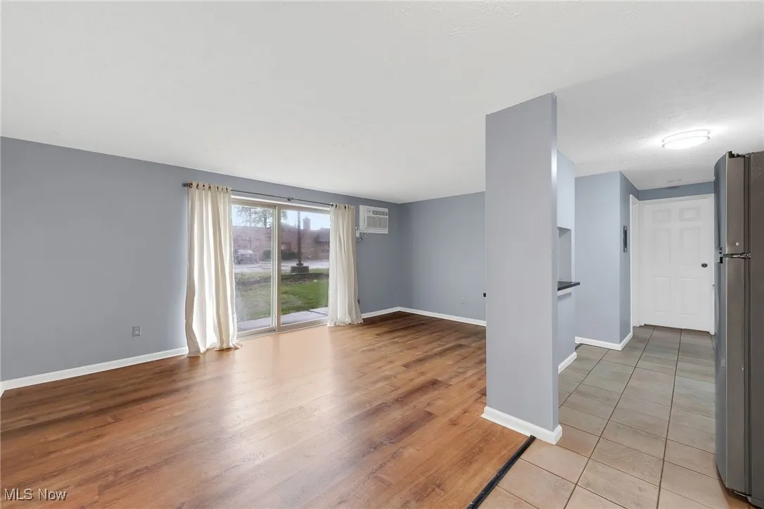 Unfurnished room with an AC wall unit and light wood-style floors