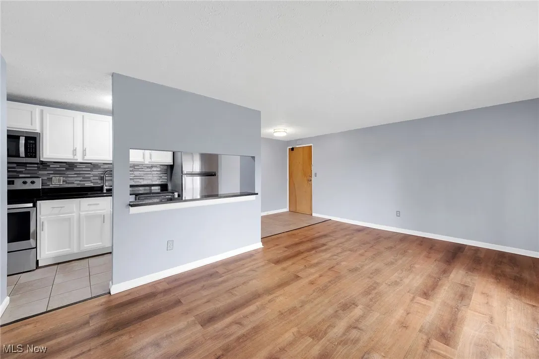 Unfurnished living room featuring light wood finished floors and baseboards