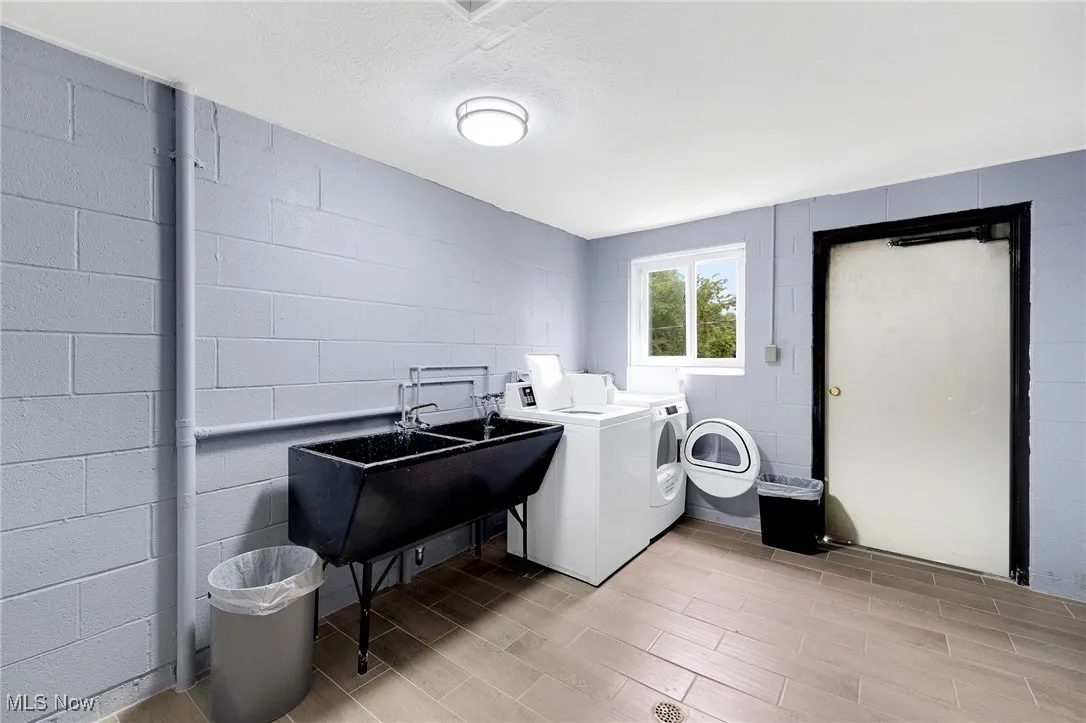Laundry area with independent washer and dryer, light wood finished floors, and concrete block wall