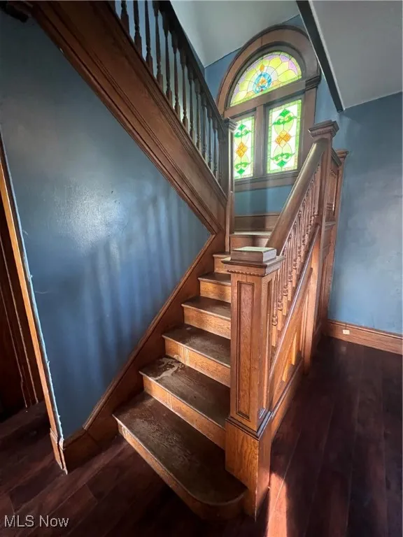 Stairway with wood-type flooring and vaulted ceiling