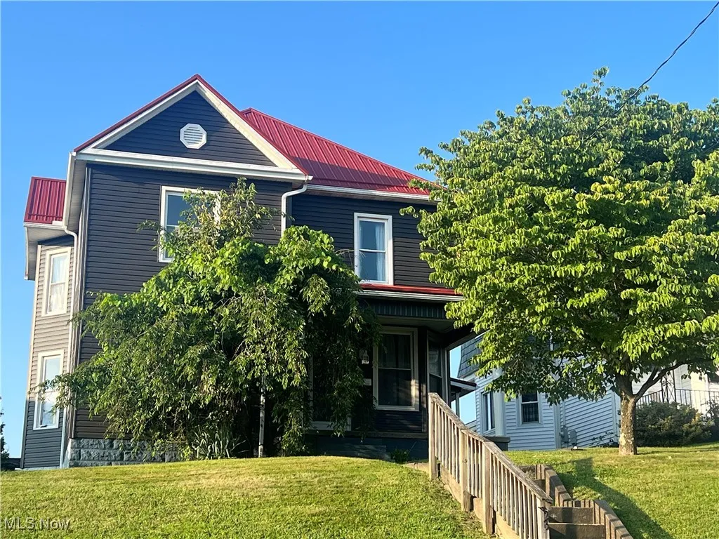 View of front of home with a front yard and a metal roof