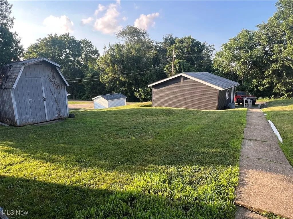 View of green lawn featuring a storage unit