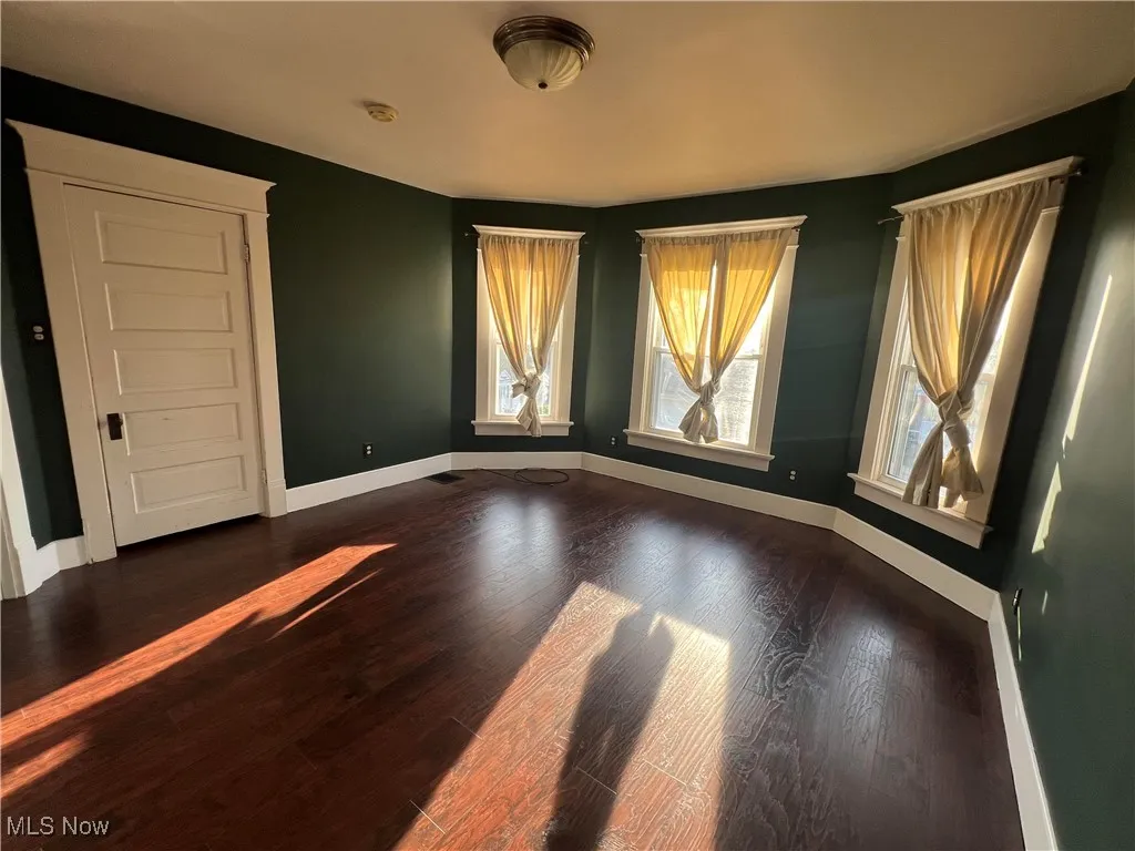 Spare room featuring baseboards and dark wood-style floors