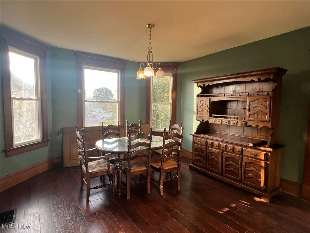 Dining space with dark wood-type flooring and a chandelier