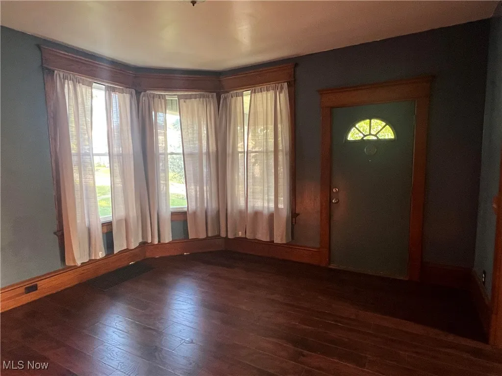 Foyer entrance with dark wood-style flooring and baseboards
