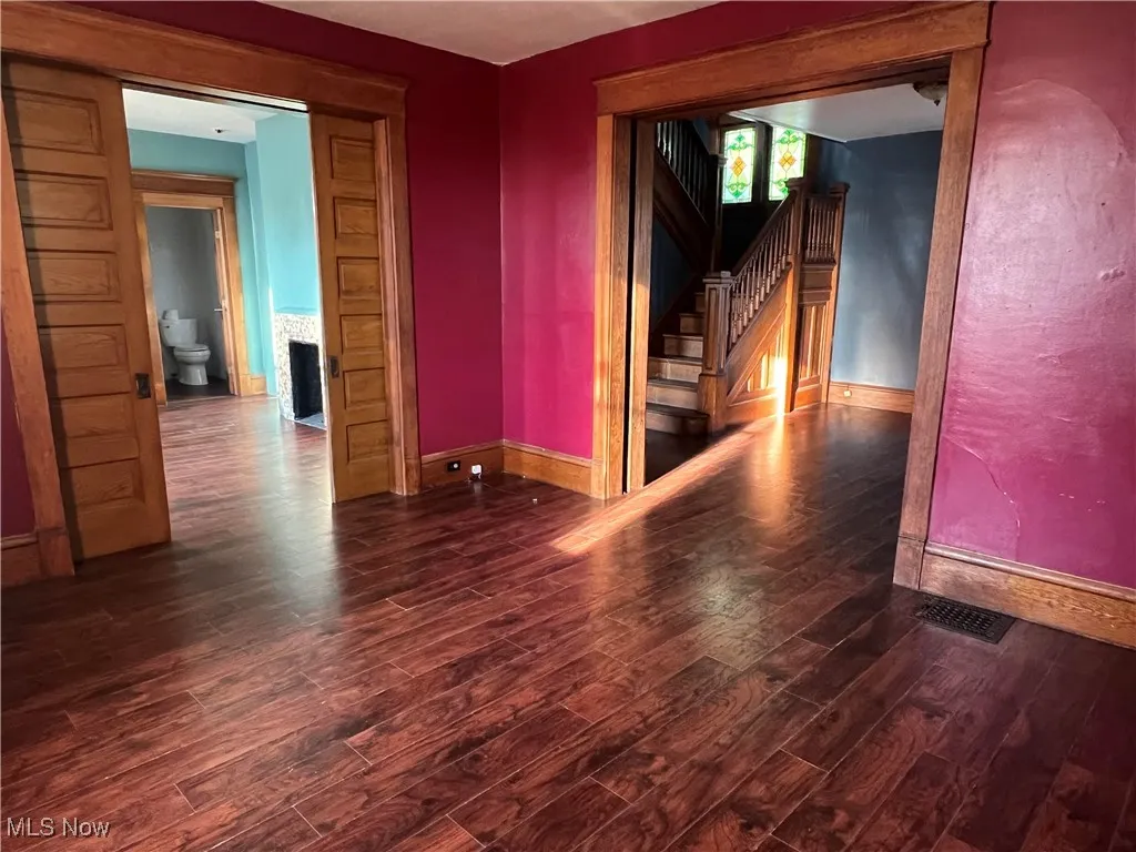 Unfurnished room featuring wood finished floors, stairway, and a fireplace
