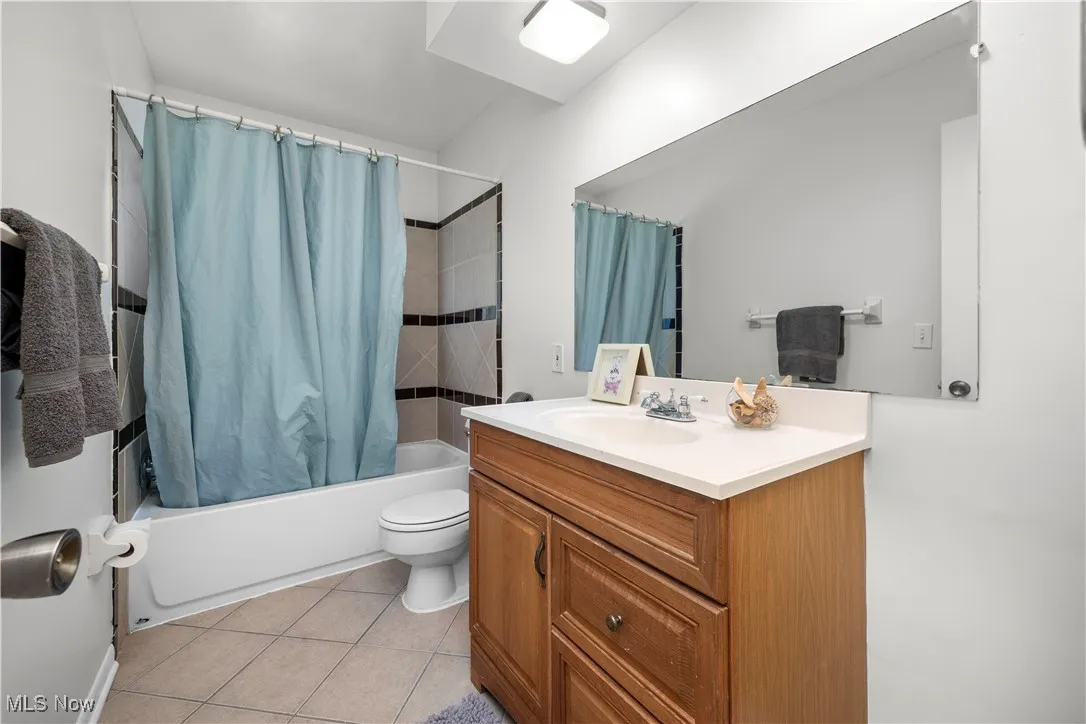 Full bath with vanity, shower / tub combo with curtain, and tile patterned floors