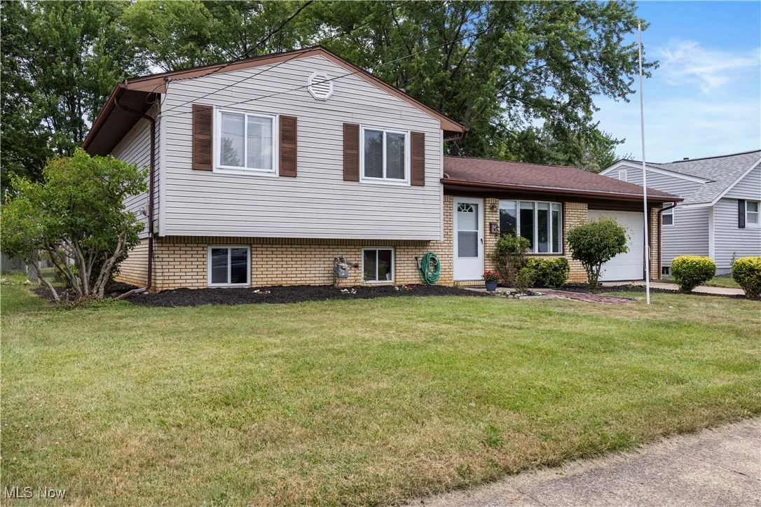 Split Level home featuring a front yard, an attached garage, and brick siding