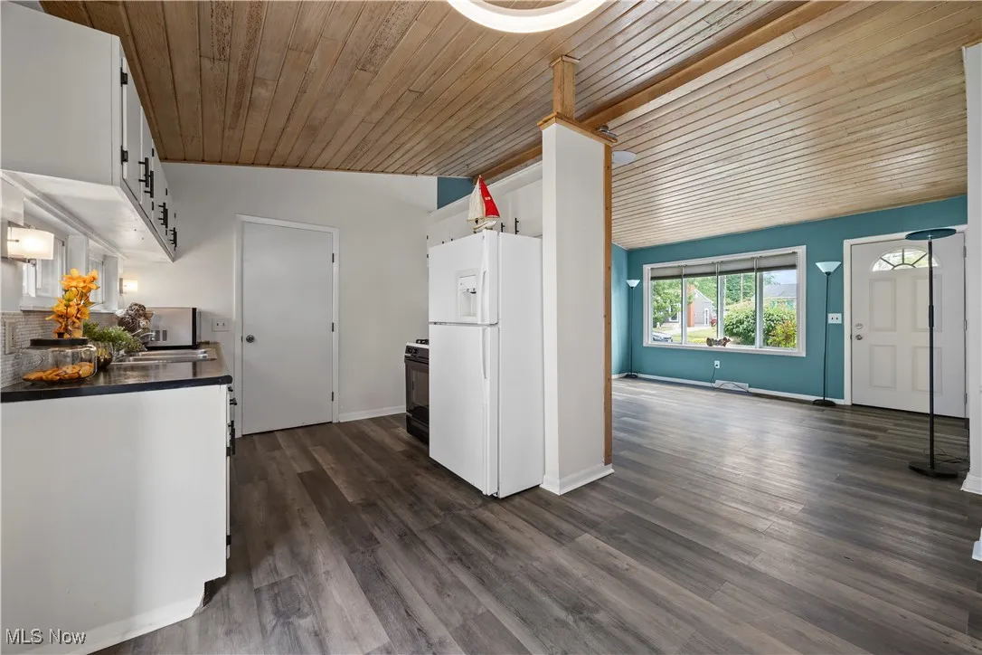 Kitchen featuring white refrigerator with ice dispenser, wooden ceiling, vaulted ceiling, dark wood-type flooring, and gas stove