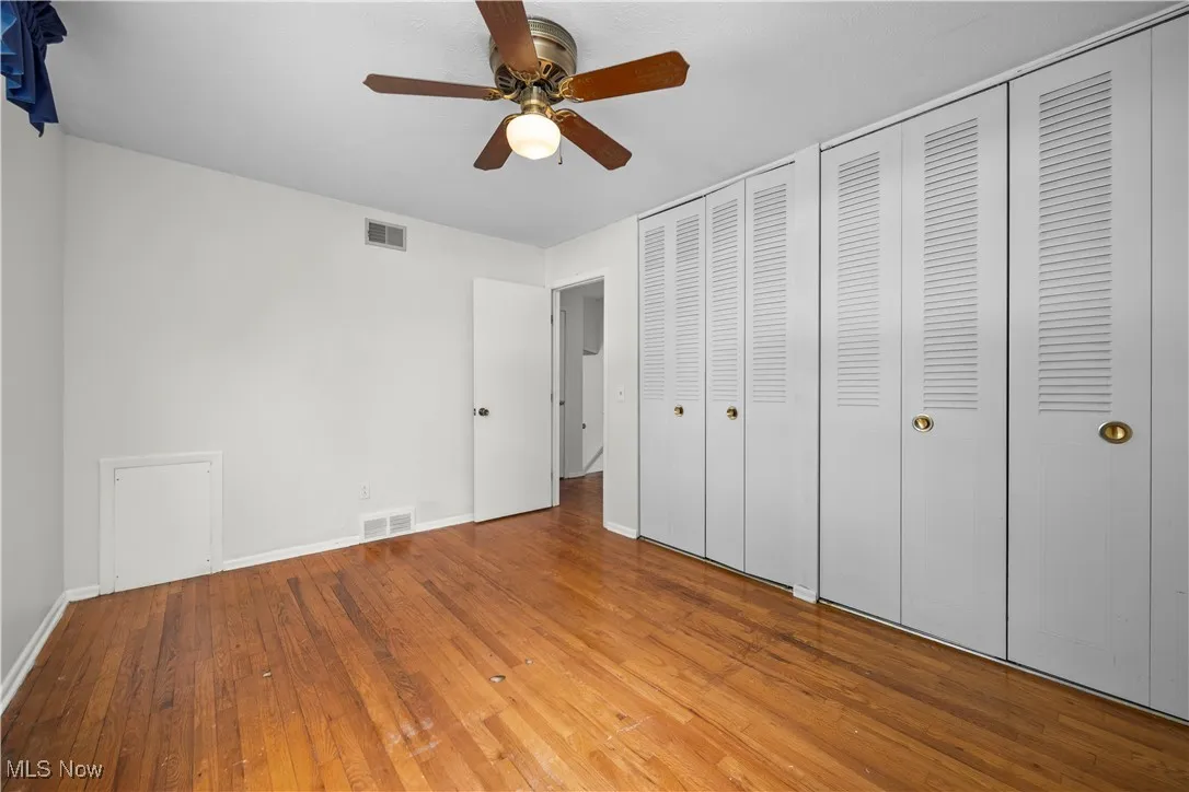 Unfurnished bedroom featuring hardwood / wood-style flooring, two closets, and ceiling fan