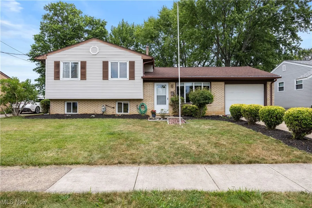 Split level home with a garage, a front lawn, and brick siding