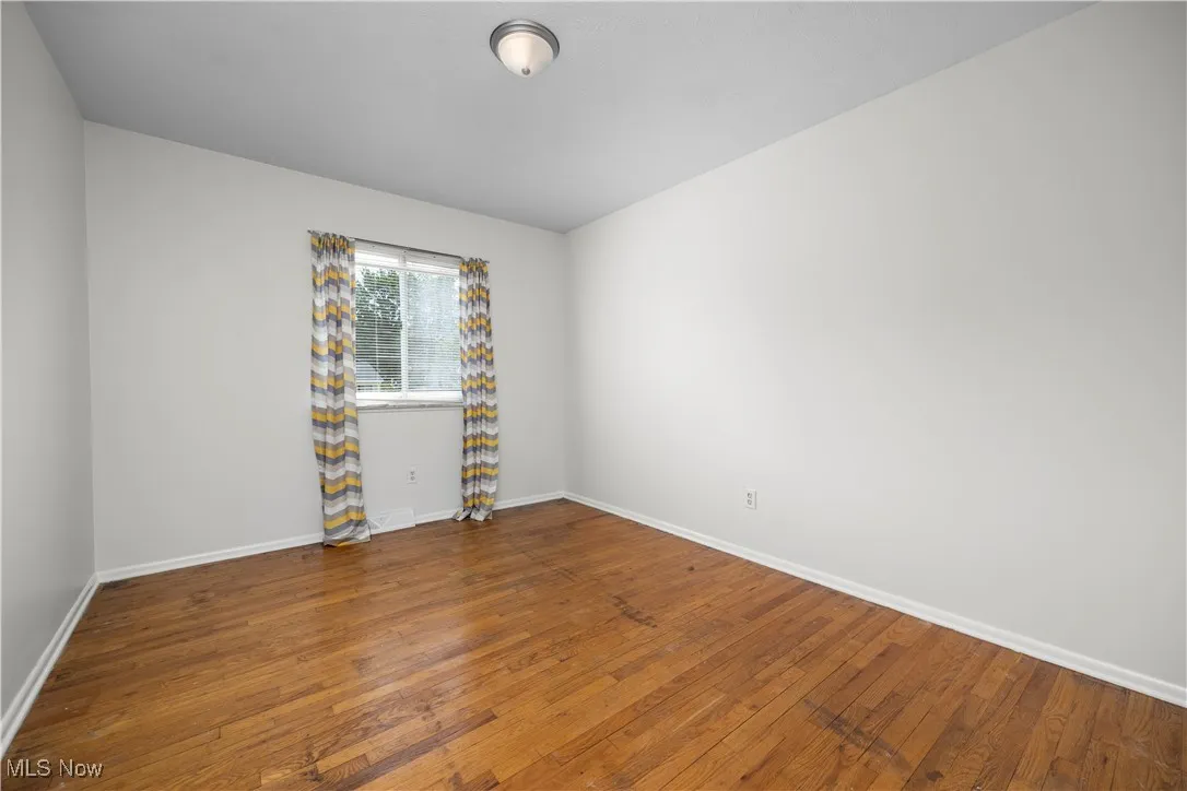 Unfurnished room featuring hardwood / wood-style floors and baseboards