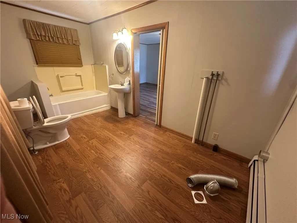 Full bath with wood finished floors and a tub to relax in