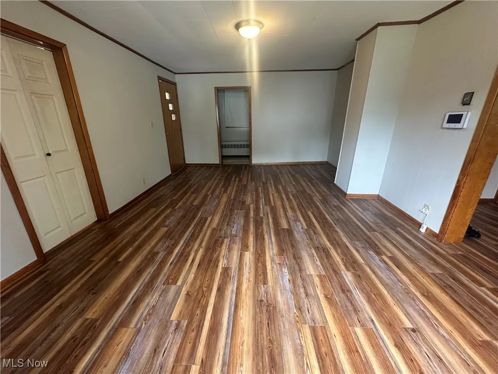 Spare room with wood finished floors and crown molding