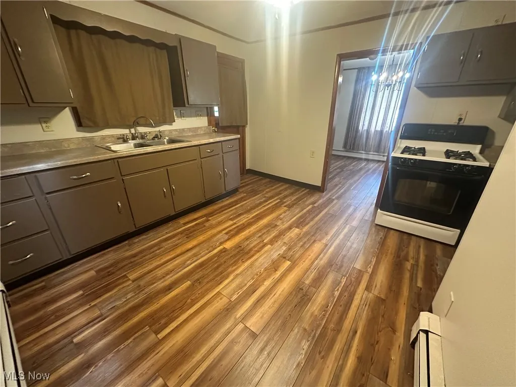 Kitchen featuring gray cabinetry, range with gas cooktop, dark wood-style flooring, and a chandelier