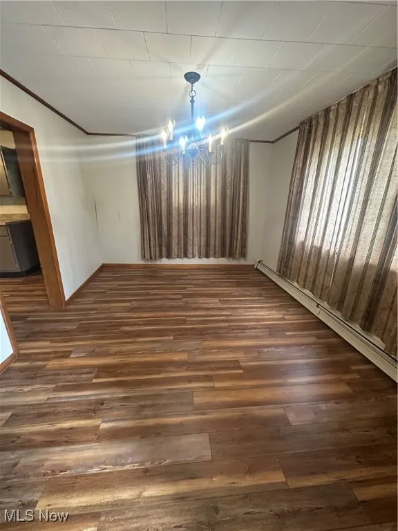 Empty room with wood finished floors and a baseboard heating unit