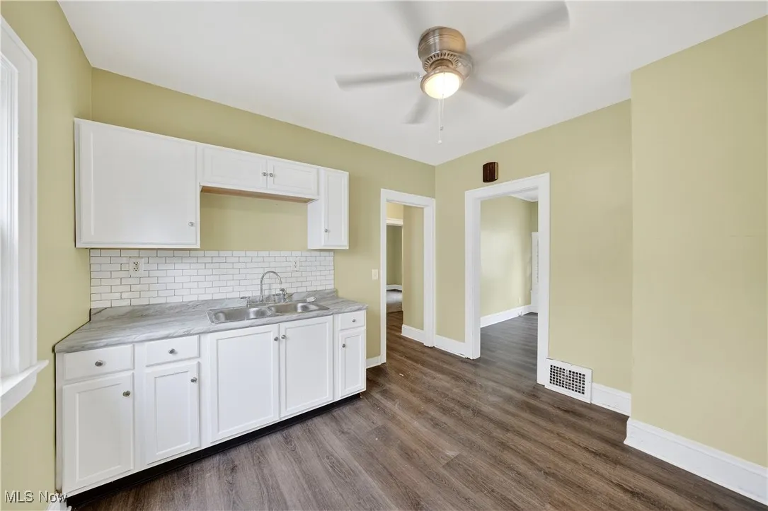 Kitchen featuring a ceiling fan, dark wood-style flooring, and white cabinets