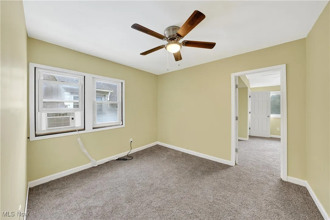 Carpeted spare room featuring a ceiling fan and cooling unit