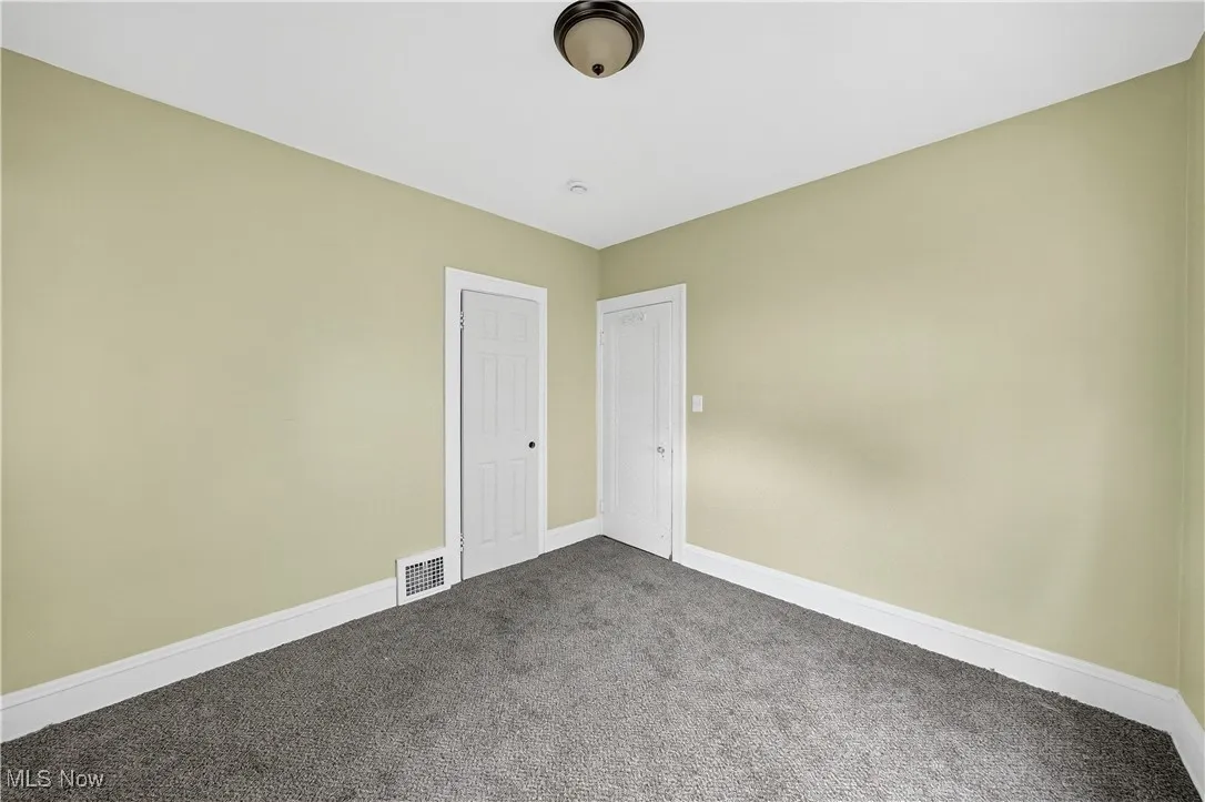 Empty room featuring dark carpet and baseboards