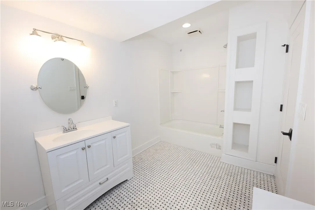 Full bath featuring vanity and washtub / shower combination