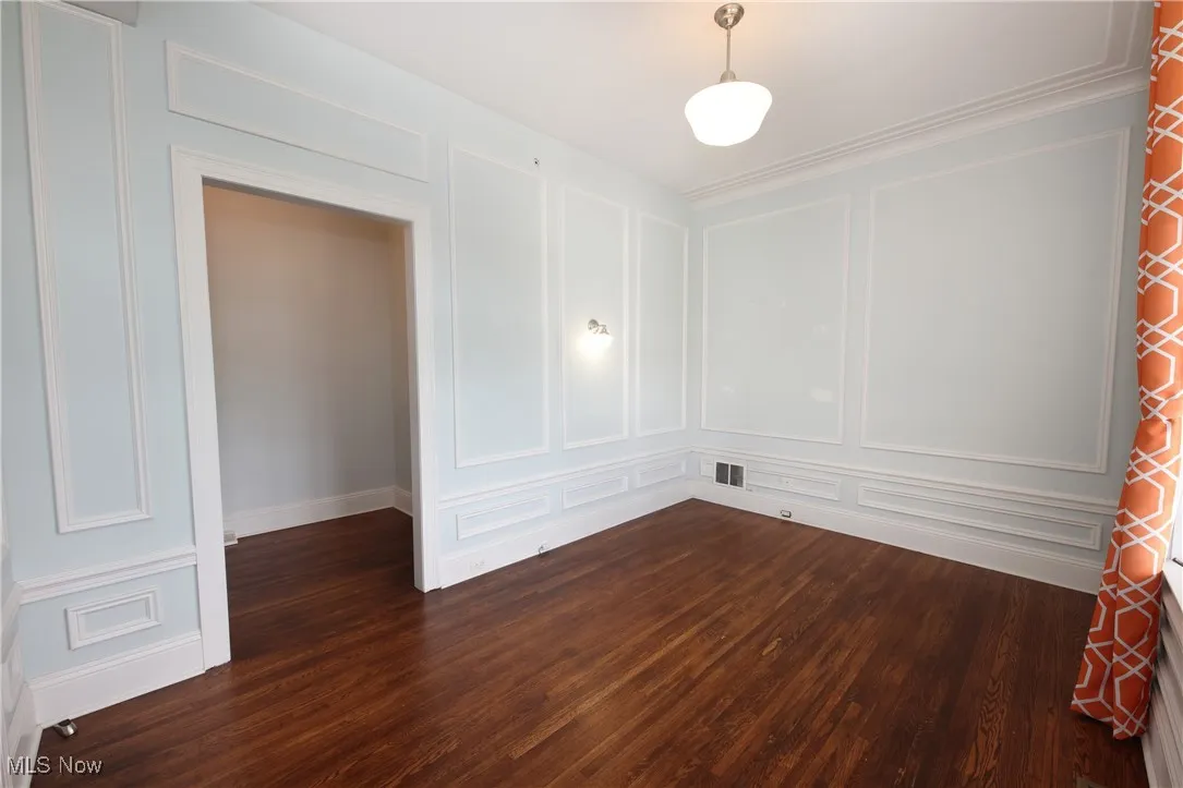 Spare room featuring a decorative wall and dark wood-style flooring