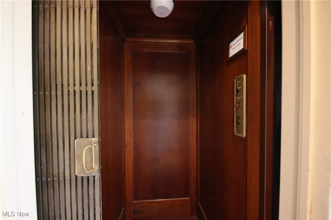 Elevator featuring ornamental molding, wood walls, and wooden ceiling