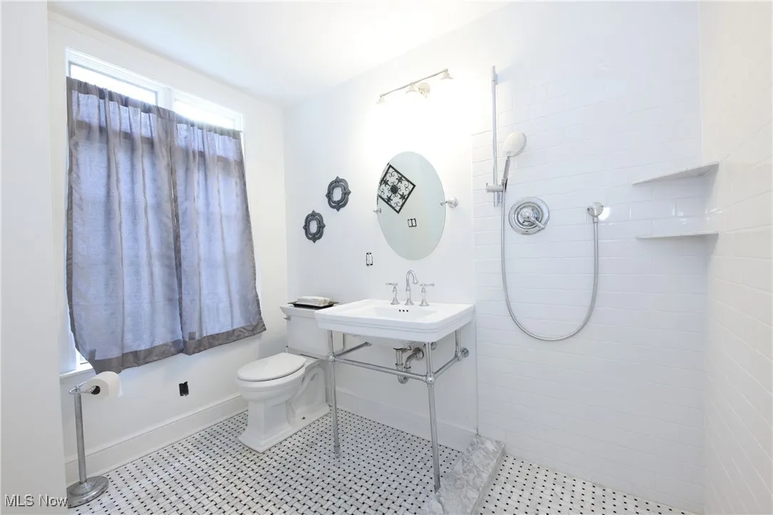 Full bath with tiled shower and toilet