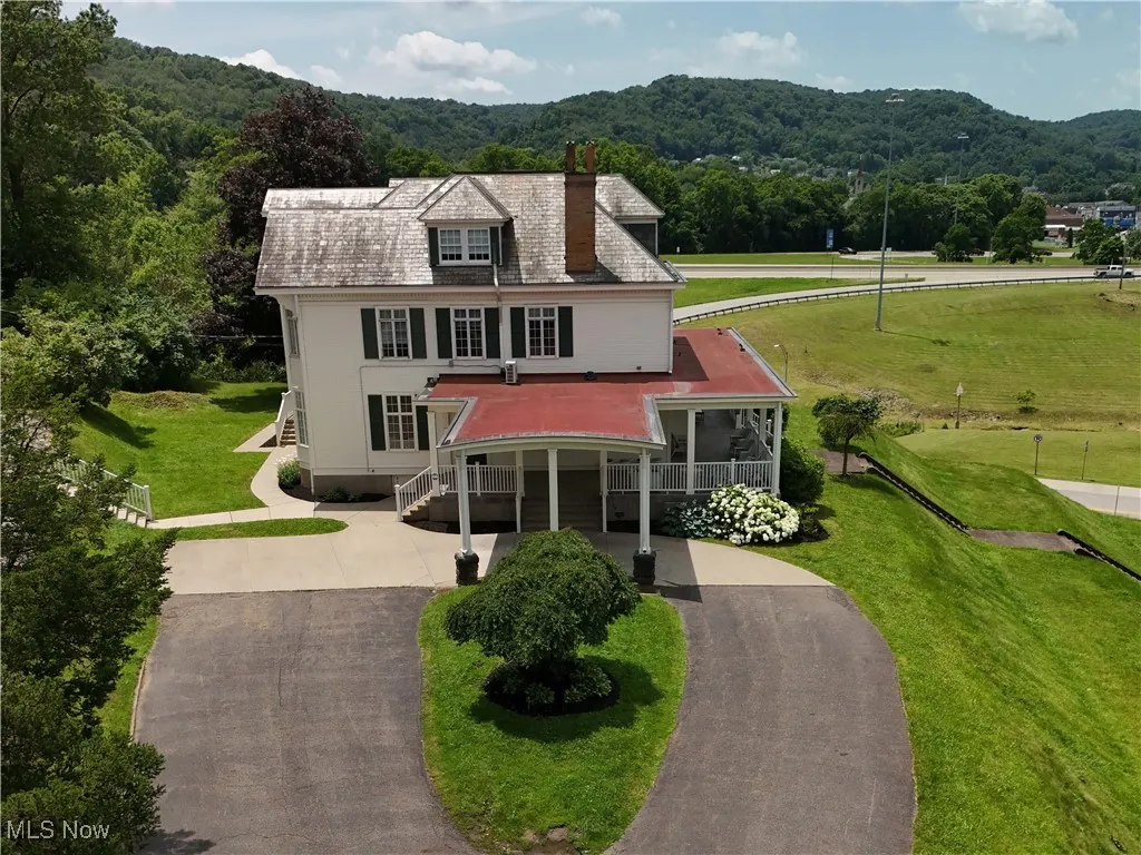 View of front facade with concrete driveway, a chimney, a forest view, and a front yard