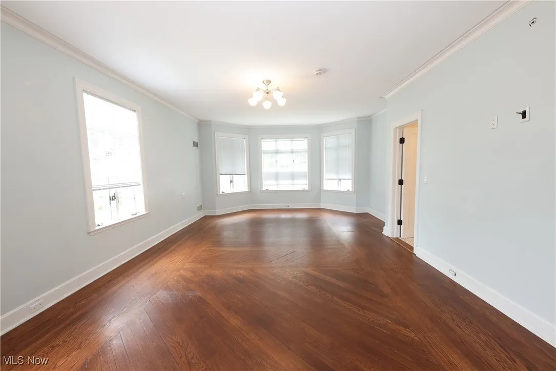 Unfurnished room with crown molding, a chandelier, plenty of natural light, and a smoke detector