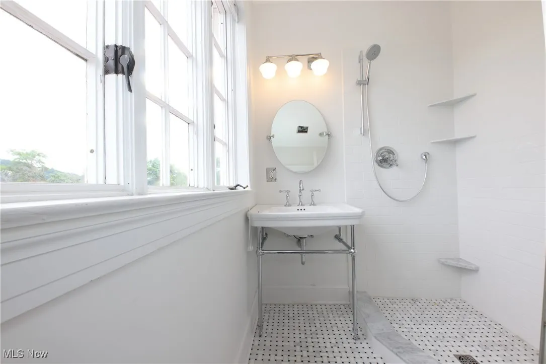 Bathroom featuring tiled shower and a sink