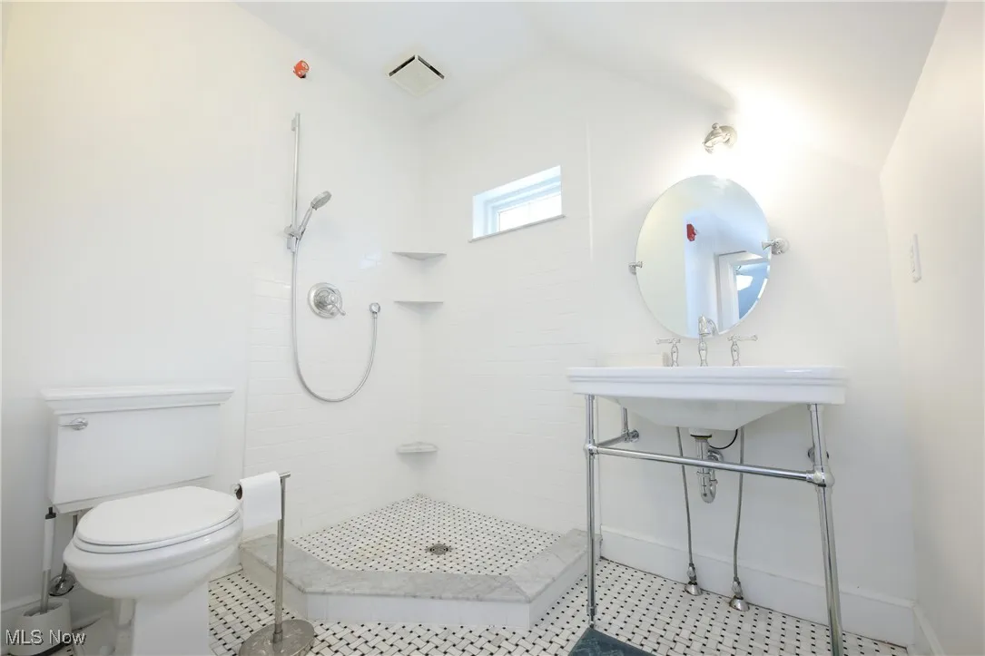 Full bathroom featuring tiled shower and vaulted ceiling