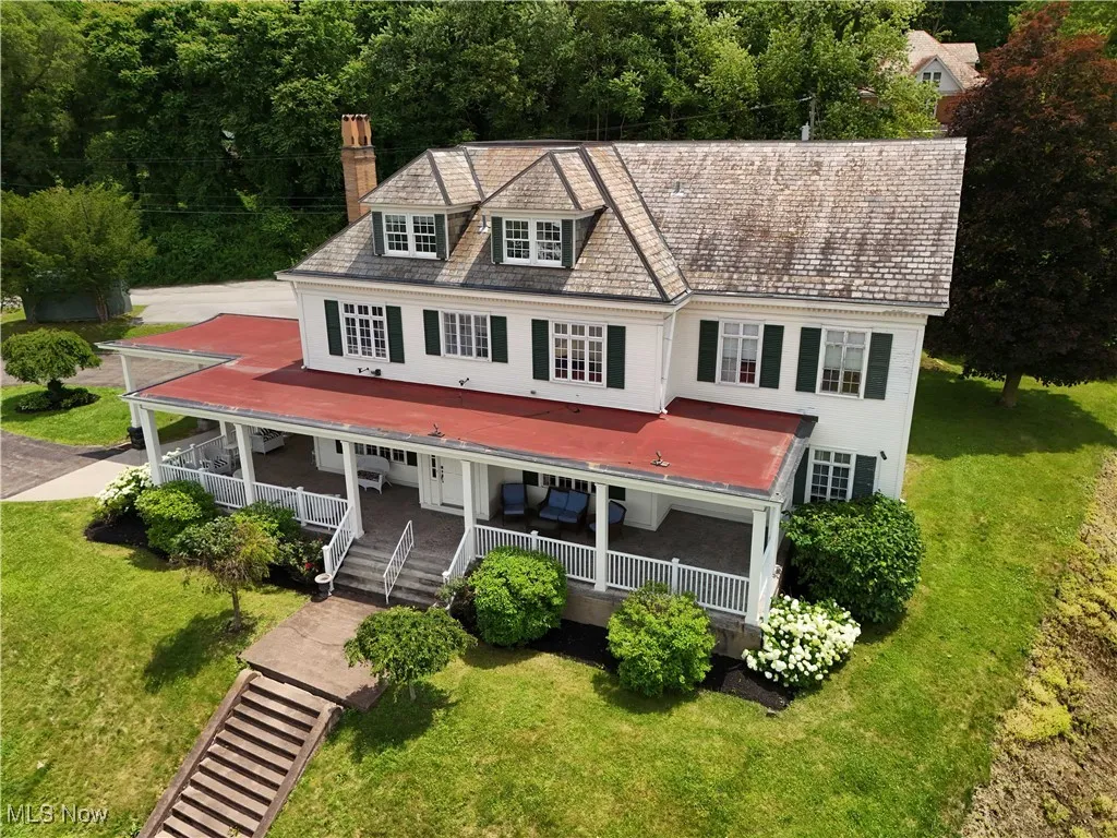 View of front of property with a porch, a chimney, and a front yard