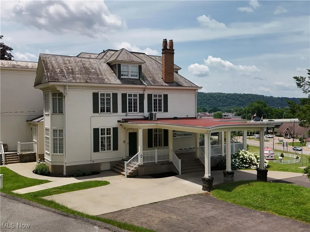 View of front of property featuring a chimney, a high end roof, and driveway
