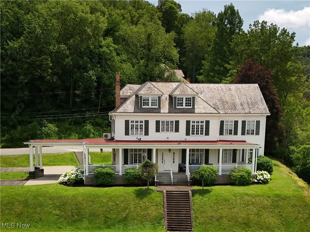 View of front of property with a chimney, covered porch, a front lawn, and driveway