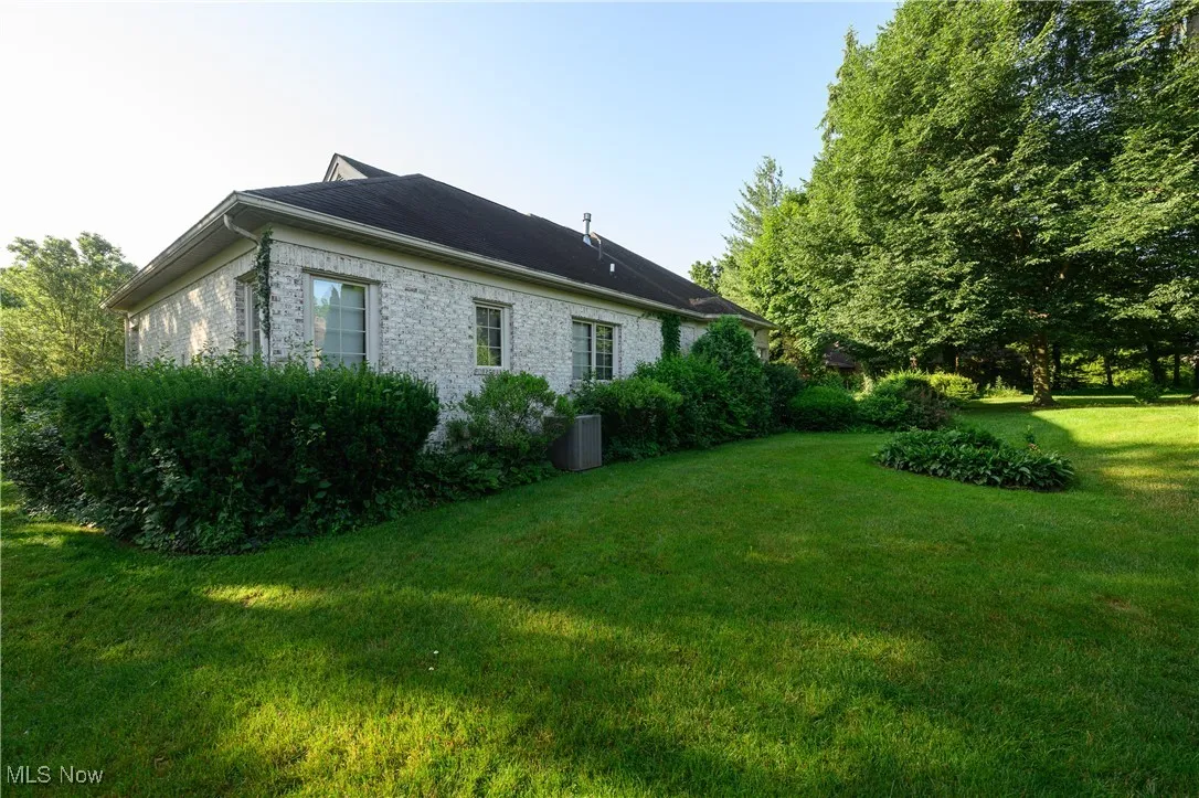 View of side of property with a lawn and brick siding