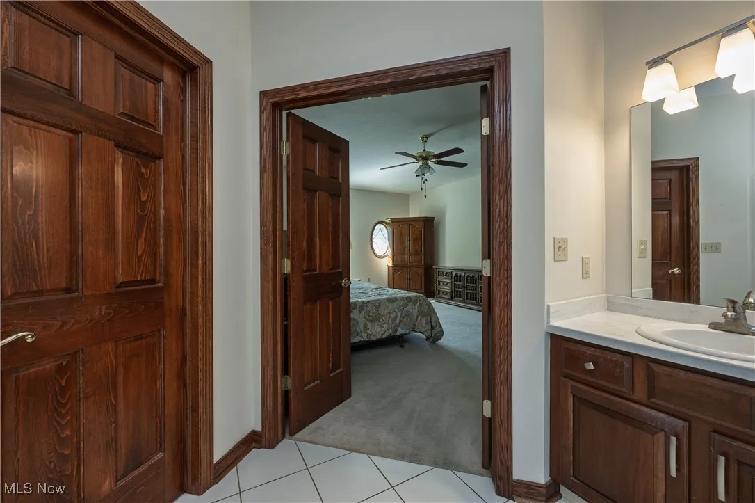 Bathroom featuring vanity, tile patterned floors, ensuite bath, and ceiling fan