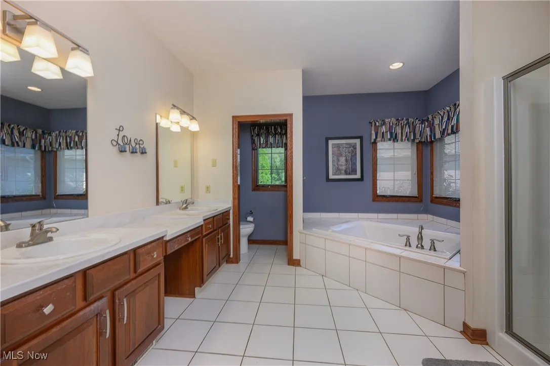Bathroom featuring double vanity, a bath, a shower stall, and tile patterned floors