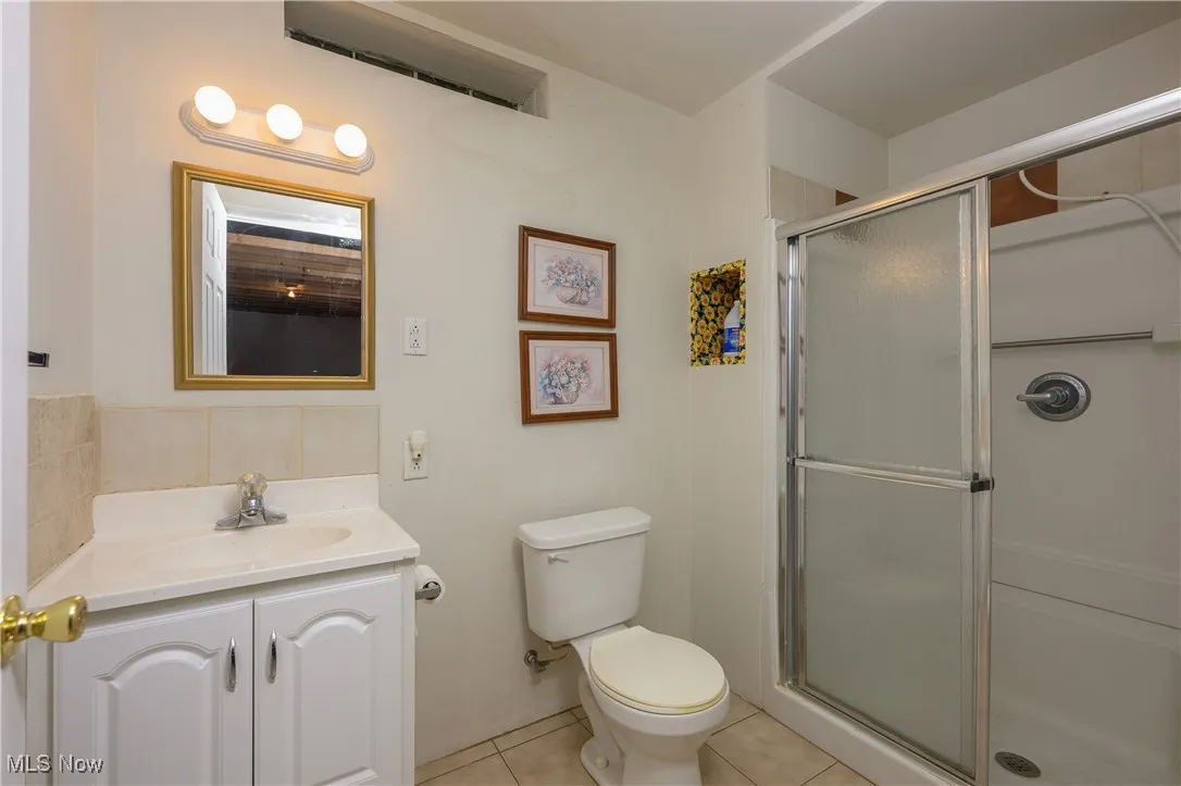 Bathroom with tile patterned floors, vanity, and a shower stall