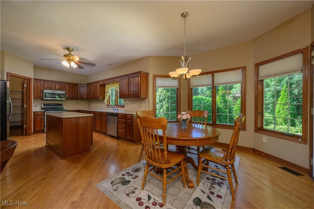 Dining room featuring light wood finished floors, a chandelier, and a ceiling fan