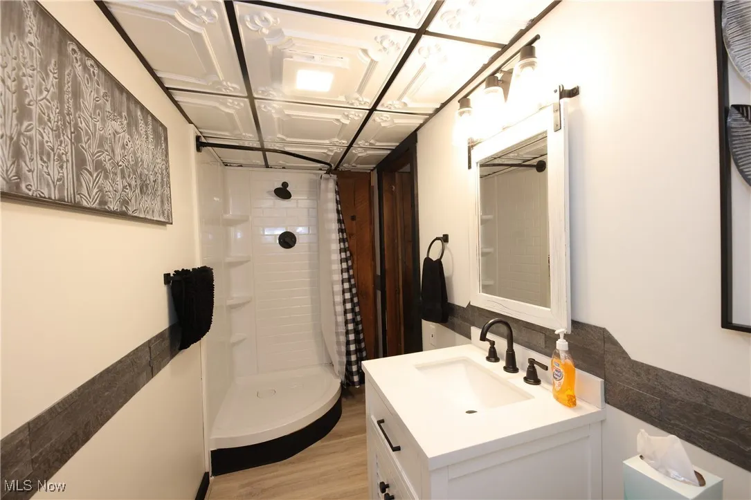 Full bathroom with vanity, wood finished floors, and curtained shower