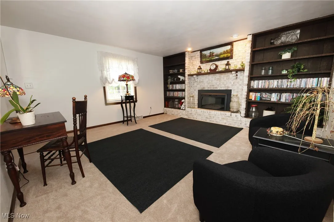Living room with light carpet, a brick fireplace, and built in features