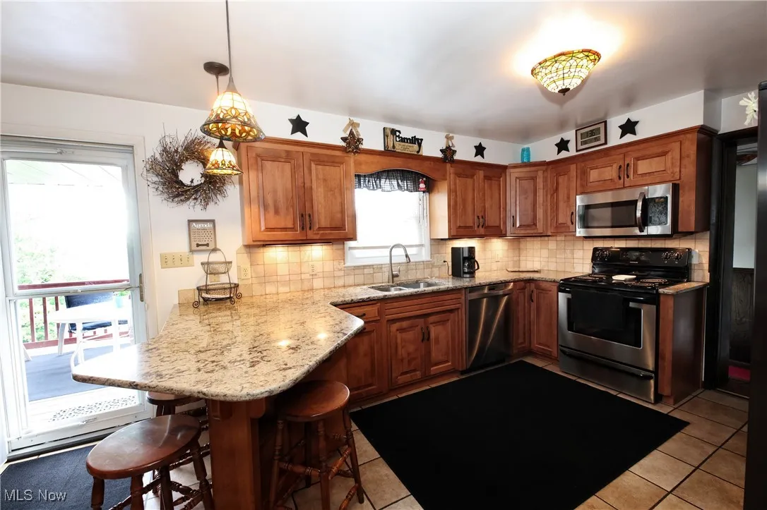 Kitchen with appliances with stainless steel finishes, a peninsula, a breakfast bar area, and decorative backsplash