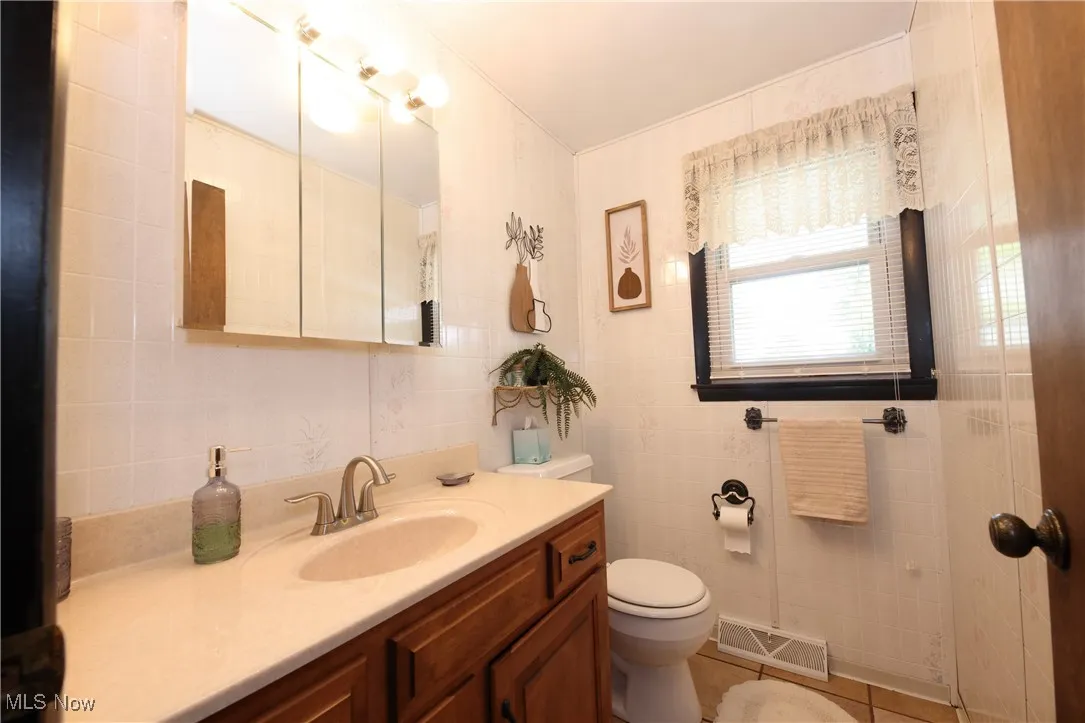 Bathroom with tile walls, vanity, and tile patterned flooring