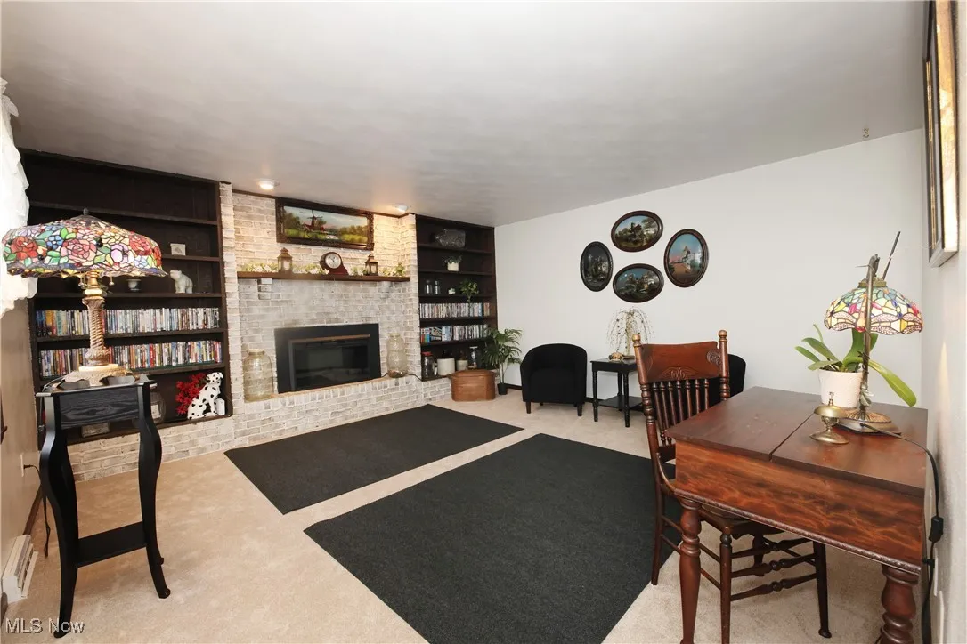 Living area with built in shelves, carpet, and a fireplace