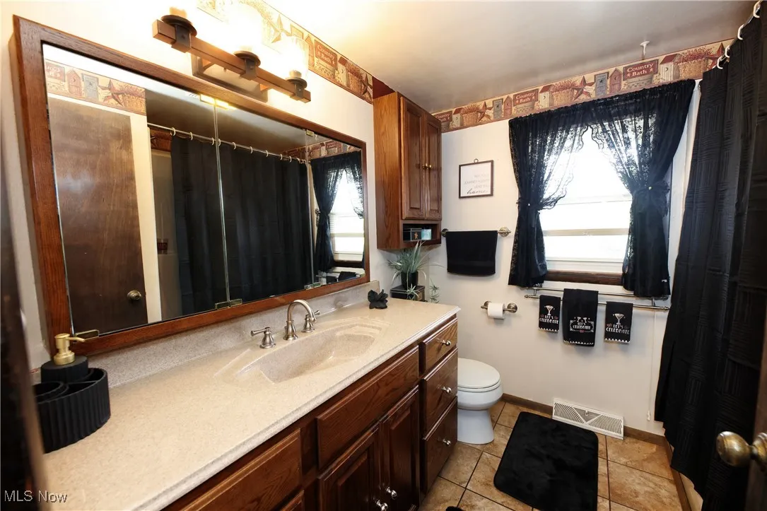Full bathroom with vanity, tile patterned flooring, and a shower with shower curtain